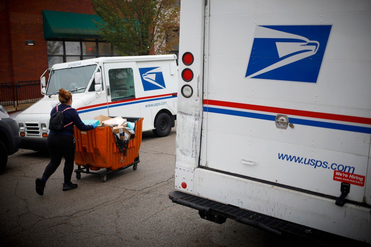 a postal worker worker pushes a mail cart outside a United States Postal Service (USPS) distribution center in Chicago.