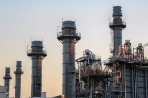 Natural gas power plant smoke stacks stand against a twilight sky.