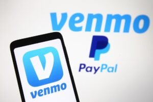 Venmo logo, a mobile payment service of PayPal is seen displayed on a smartphone and a PC screen.