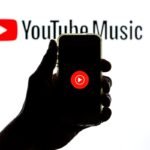 The YouTube Music app seen displayed on a smartphone screen and a YouTube Music logo in the background.