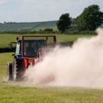 Farmer spreading chicken manure mixed with lime on newly harvested meadow