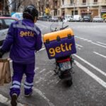 Getir delivery driver holding grocery bags and walking to Getir delivery bike