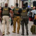 Immigration and Customs Enforcement (ICE) agents as travelers wait in line to be screened at a Transportation Security Administration (TSA) checkpoint at Hartsfield-Jackson Atlanta International Airport (ATL) in Atlanta, Georgia, US, on Monday, March 23, 2026.