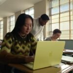 young woman seated at a classroom desk using a MacBook Neo