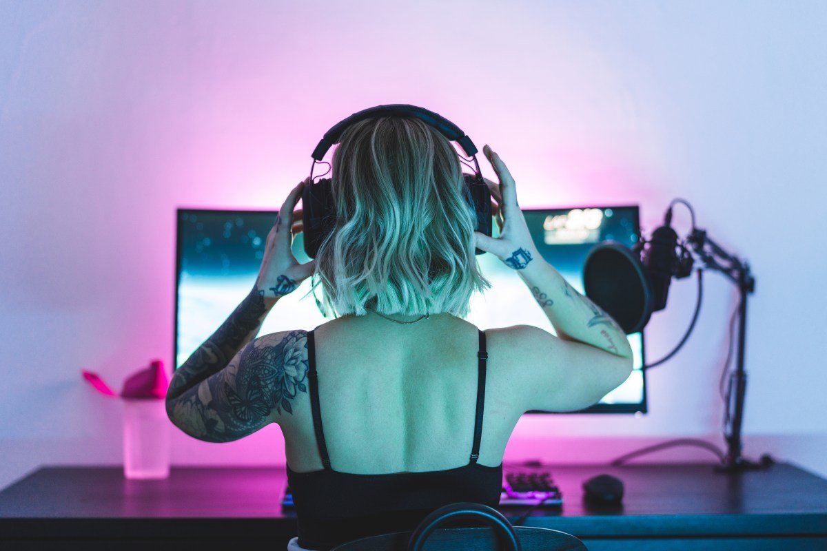 Image of a woman putting on headphones in front of a computer screen and microphone.