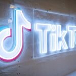TikTok's neon logo and music note symbol on a concrete wall