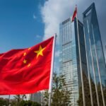 The vibrant red field and yellow stars of the Flag of the People's Republic of China flying in the breeze beside the futuristic glass and steel towers of Pudong's soaring skyscrapers, Shanghai, China.