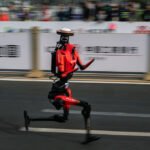 The fastest humanoid robot, an H1made by Honor, runs beside human runners at the start on its way to winning the Beijing Humanoid Half Marathon.