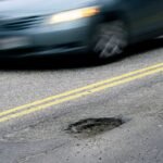 CAPE ELIZABETH, ME - FEBRUARY 22: A car drives past a pothole on Forest Ave. in Portland Tuesday, February 22, 2022. (Shawn Patrick Ouellette/Portland Press Herald via Getty Images)