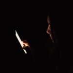 Lady looking at smartphone in dark room.