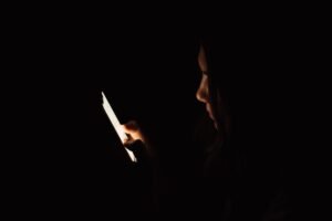 Lady looking at smartphone in dark room.