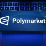 In this photo illustration, a Polymarket logo is displayed on a smartphone on top of a laptop.