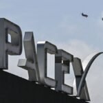 US billionaire businessman and pilot Jared Isaacman flies in formation aboard a fighter jet over the SpaceX sign, close to the Starship spacecraft, before his third test flight from Starbase in Boca Chica, Texas, on March 13, 2024.